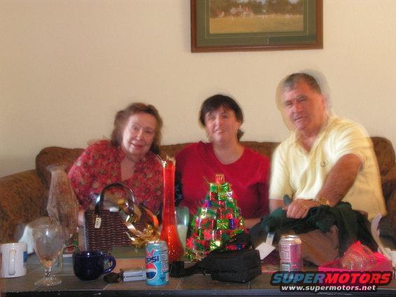 Three people on a couch with a Christmas tree and Pepsi can on the table