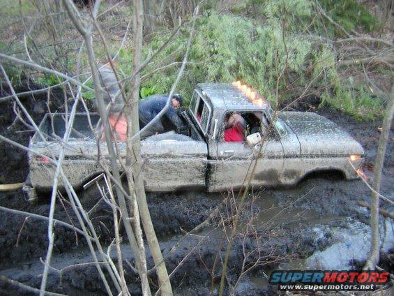 1978 Ford F-250 stuck in mud with two people inside, one in driver's seat, other leaning over from passenger side