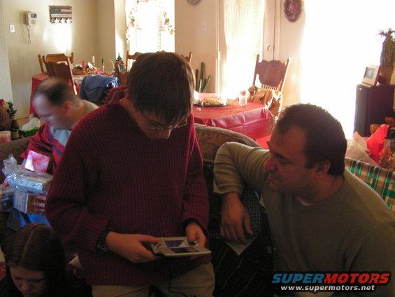Two guys looking at a handheld video game console in a living room