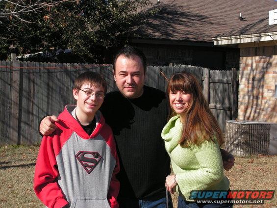Man, woman, and boy posing for a photo in a backyard