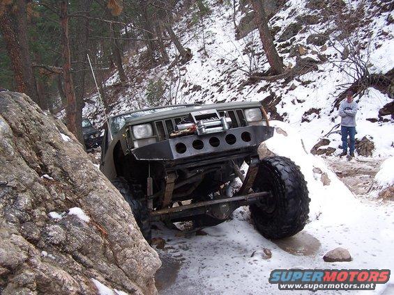 Olive green off-road SUV navigating rocky, snowy terrain