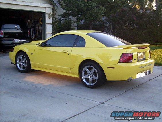 Yellow 2002 Ford Mustang coupe, rear 3/4 view. Visible 'Mustang' badging
