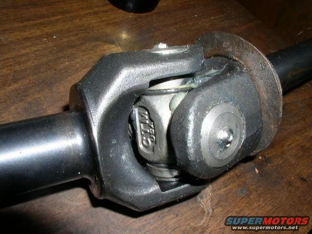 Driveshaft U-joint with CTMS USA marking. Part is on a wooden surface