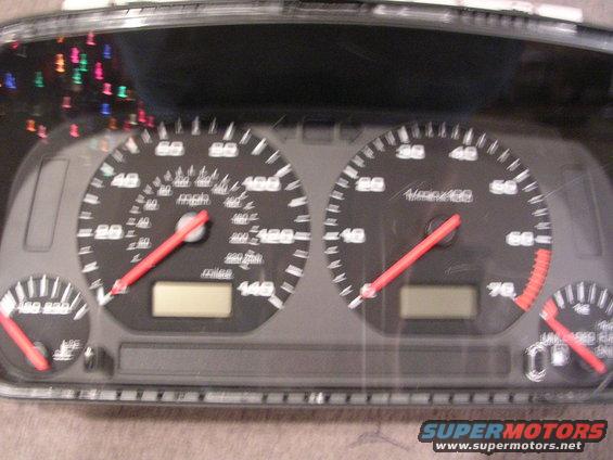 Car dashboard with speedometer, tachometer, and fuel gauge. Red needles point to readings