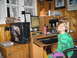 1986 Ford Bronco - A young boy smiles while sitting at a computer desk filled with various electronics and gaming accessories.
