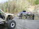 1978 Ford Bronco - Two off-road vehicles are on a dirt road with trees and rocks in the background. People are attending to the buggy.