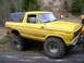 1978 Ford Bronco - A yellow 1978 Ford Bronco is parked on the side of a dirt road with large off-road tires.