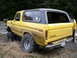 1978 Ford Bronco - Yellow 1978 Ford Bronco with large tires is stuck in the mud off-road.