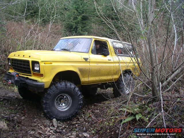 Yellow 1978 Ford Bronco off-roading through trees