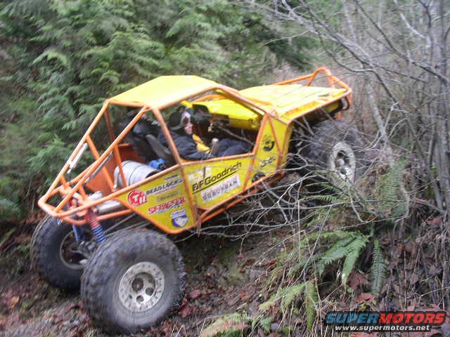 Yellow off-road buggy with roll cage navigating a wooded trail