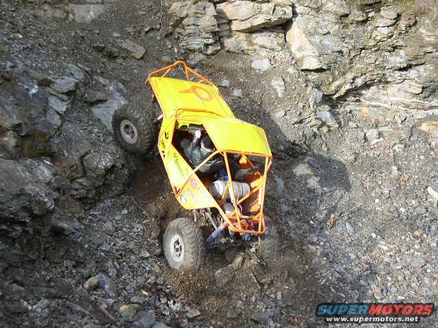 Yellow off-road vehicle with roll cage climbing a rocky incline