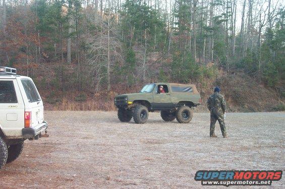 Olive green lifted SUV with large tires, 3/4 front view