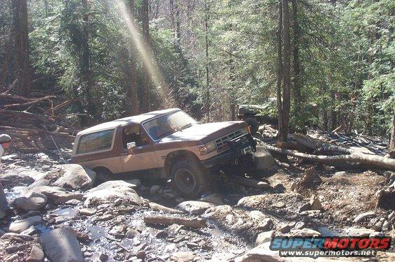 Brown and white 1987 Ford Bronco navigating rocky terrain