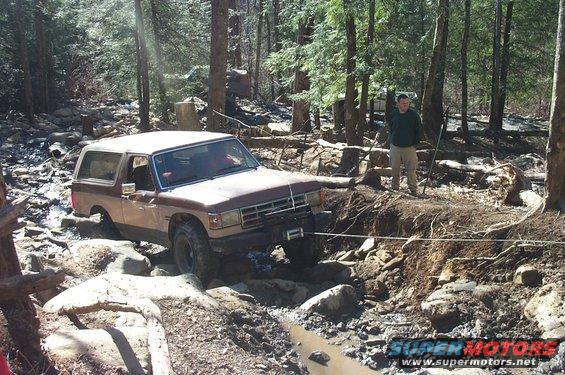 Brown and tan 1987 Ford Bronco navigating rocky terrain with a winch line attached