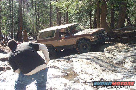 Ford Bronco navigating rocky terrain with a person watching