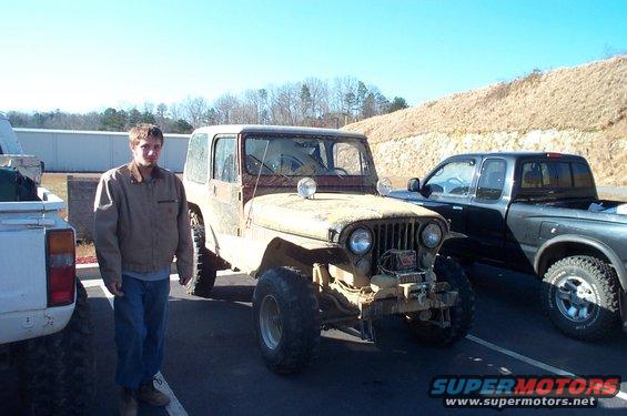 Guy standing next to a dirty Jeep CJ-7, with a white truck on the left and a black pickup truck on the right