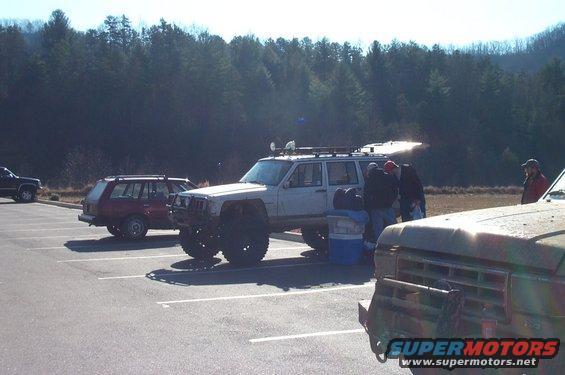 White Jeep Cherokee XJ with off-road modifications, parked in a lot