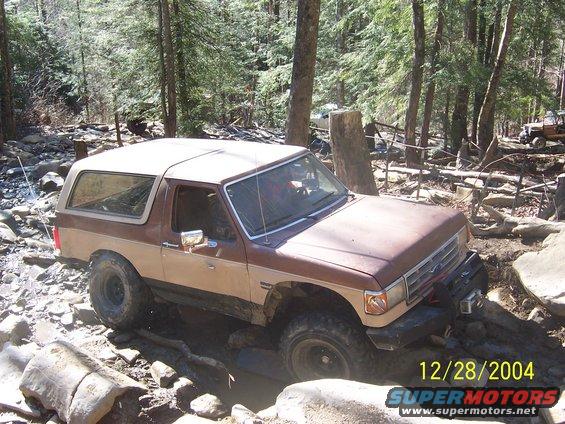 Brown and tan Ford Bronco off-roading on a rocky trail