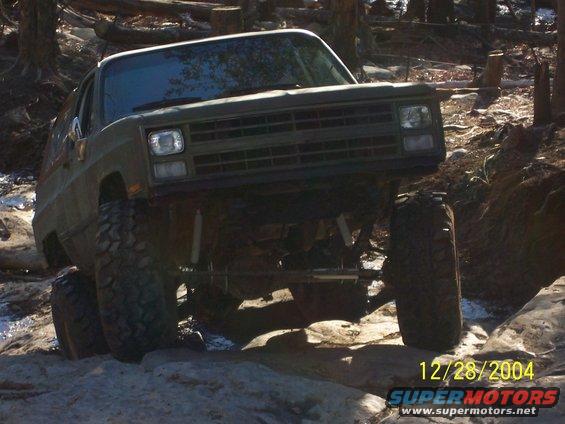 Green SUV with large tires navigating rocky terrain