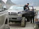 2000 Ford F-450 - A lifted black Dodge Ram pickup truck is parked in a muddy, outdoor setting with several people around it.