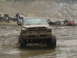 2000 Ford F-450 - Muddy Dodge Ram pickup truck navigating a challenging off-road terrain with other vehicles present.