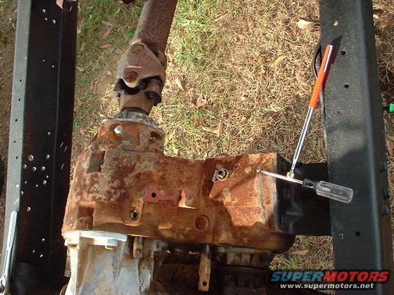 Rusted transfer case with driveshaft attached, viewed from above, with a screwdriver nearby