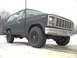 1985 Ford Bronco - A dark-colored Ford Bronco is shown from a low angle on a snowy surface, with trees in the background.