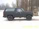 1985 Ford Bronco - A matte black Ford Bronco is parked on a snowy surface with trees in the background.