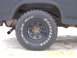 1985 Ford Bronco - A close-up view of a truck's tire and wheel well, showing tire brand details and part of the vehicle's body.