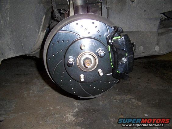 Drilled and slotted brake rotor with black caliper and green accents