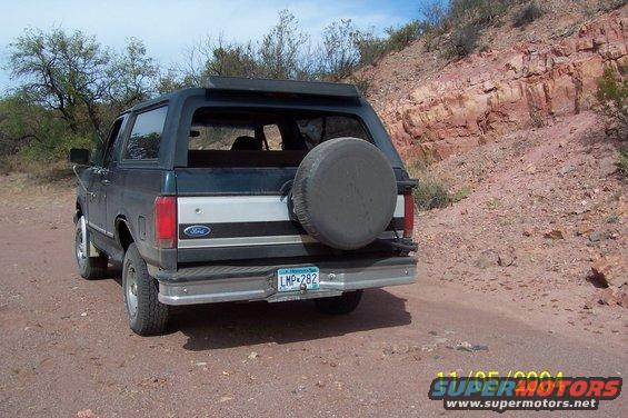 Dark green Ford Bronco with a spare tire on the rear, parked on a dirt road