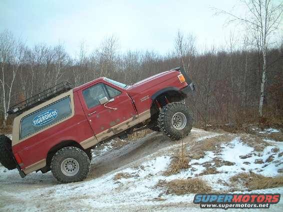 Red Ford Bronco with "BIGBRONCOS" decal on side, climbing a snowy hill