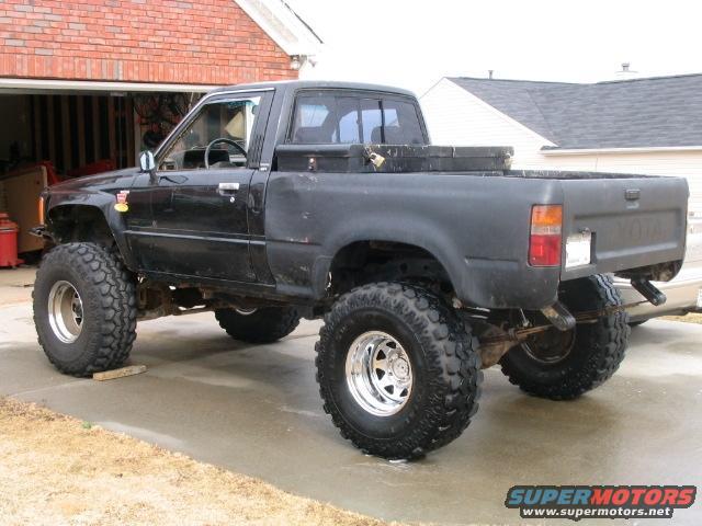 Black lifted Toyota pickup truck with large off-road tires parked in a driveway