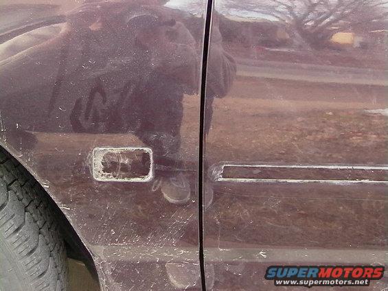 Close-up of a car's side door showing a missing trim piece and some dirt