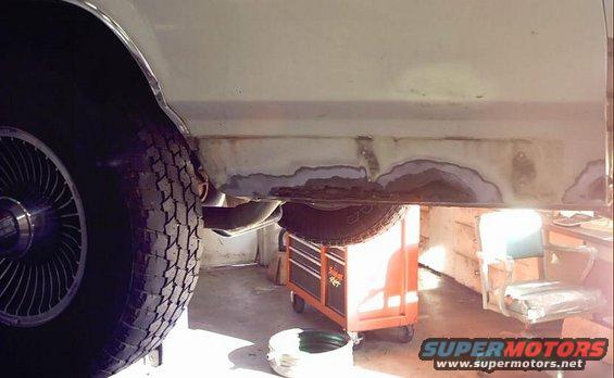 White 1985 Ford Crown Victoria LTD side view showing extensive rust on the rocker panel and undercarriage