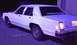 1985 Ford Crown Victoria LTD - This white sedan is parked in a lot, with its rear lights on.