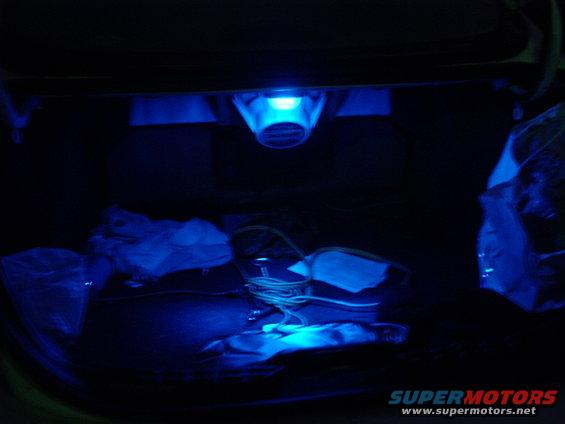 Car trunk interior with blue LED lighting and some items, including wires and plastic bags