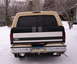 1993 Ford Bronco - Rear view of a tan and black Ford Bronco parked in the snow, showing its chrome bumper and license plate.