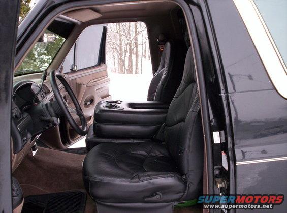 Front seats and center console of a vehicle, with a snowy outdoor scene visible through the windows
