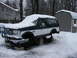 1994 Ford Bronco - A two-tone Ford Bronco sits on jack stands in a snowy yard, its wheels removed for maintenance.
