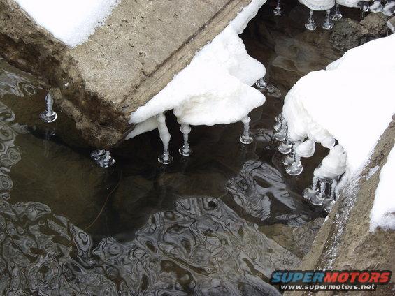 icicles hanging over water with snow on concrete