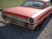 1963 Ford Galaxie - The rear of a red 1963 Ford Galaxie is visible, with gravel on the ground and grass in the background.