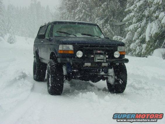 Dark blue Ford Bronco with lifted suspension and winch in deep snow, front view