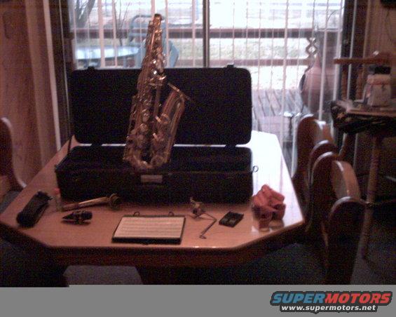Saxophone in case on a table with sheet music and accessories