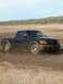 1993 Ford Bronco - A black pickup truck navigates a muddy terrain, kicking up dirt as it moves.