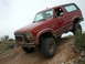 1993 Ford Bronco - This red Ford Bronco is navigating a steep, rocky incline on a dirt trail.