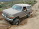 1993 Ford Bronco - This Ford Bronco is shown navigating a challenging off-road trail with steep inclines and deep ruts.