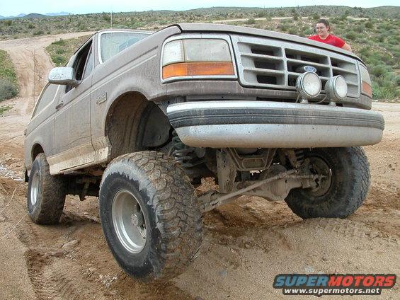 Brown Ford Bronco with lifted suspension and off-road tires on a dirt road