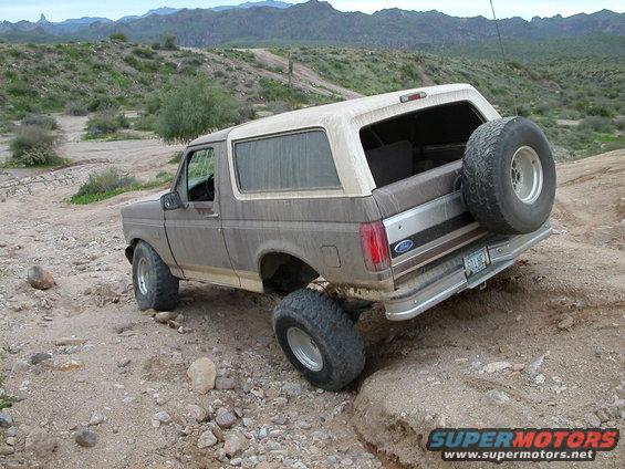 1993 Ford Bronco climbing over rocks on a desert trail