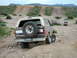 1993 Ford Bronco - This 1993 Ford Bronco is navigating a rough, dusty terrain with hills in the background.